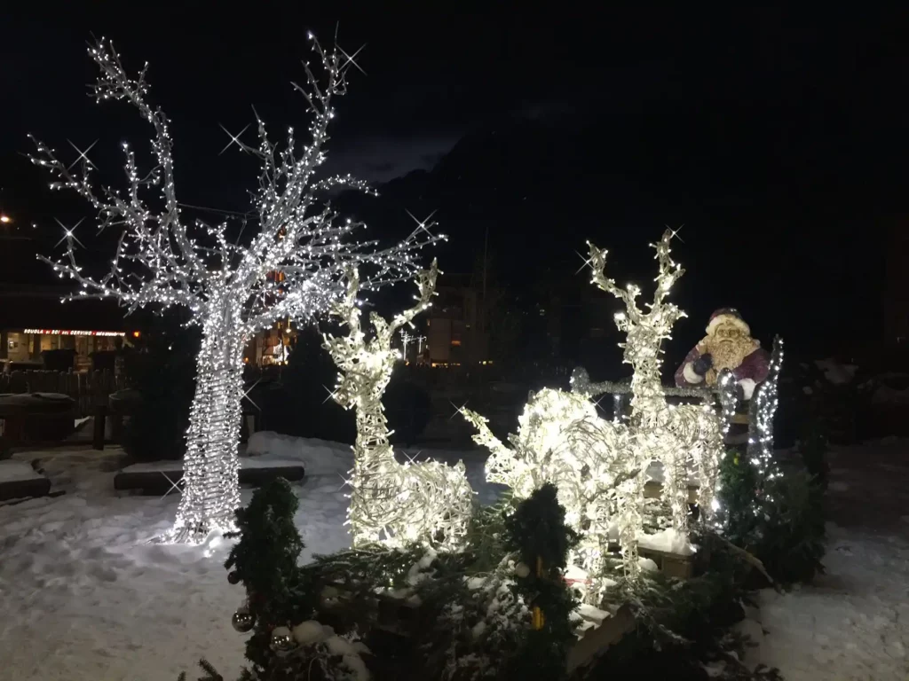 Immagine di un un parco innevato, allestito con: Babbo Natale, renne, slitta e albero artificiale LED